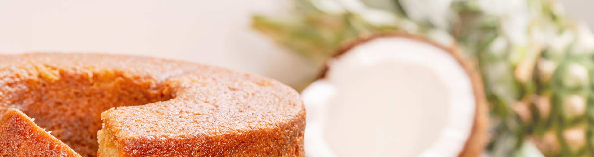 Coconut rum cake with a coconut next to it on a blurred background