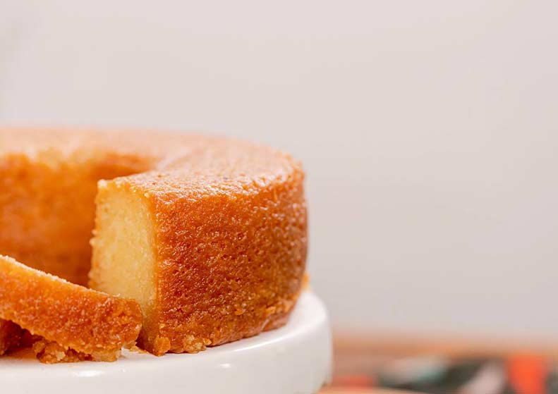 Slice of rum cake on a white plate with a blurred background