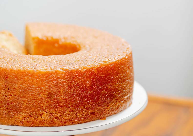 Round caribbean rumcake on a white plate with a blurred background