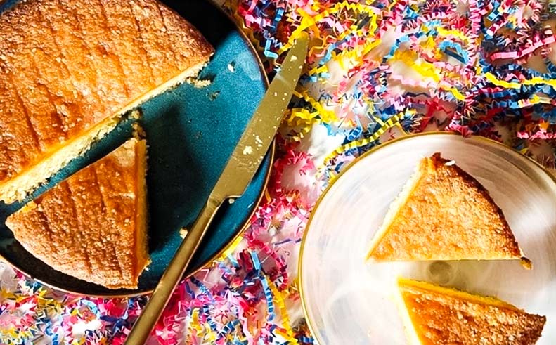 Two slices of cake on a blue plate with a knife, surrounded by colorful confetti.