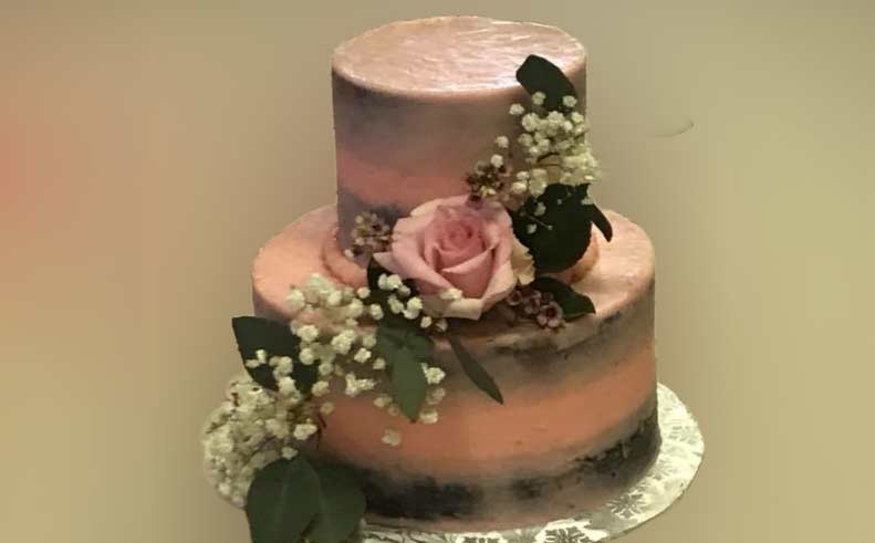 Two-tiered cake with pink flowers on a plain background