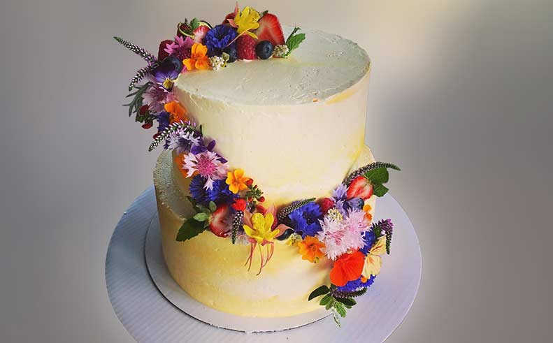 Two-tiered cake decorated with colorful flowers on a plain background
