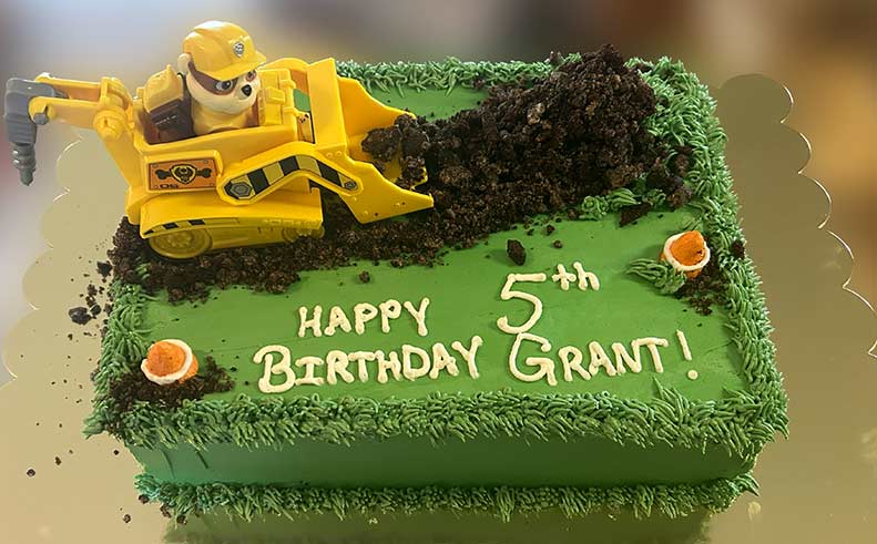 Birthday cake with a bulldozer toy and 'Happy 5th Birthday Grant!' text