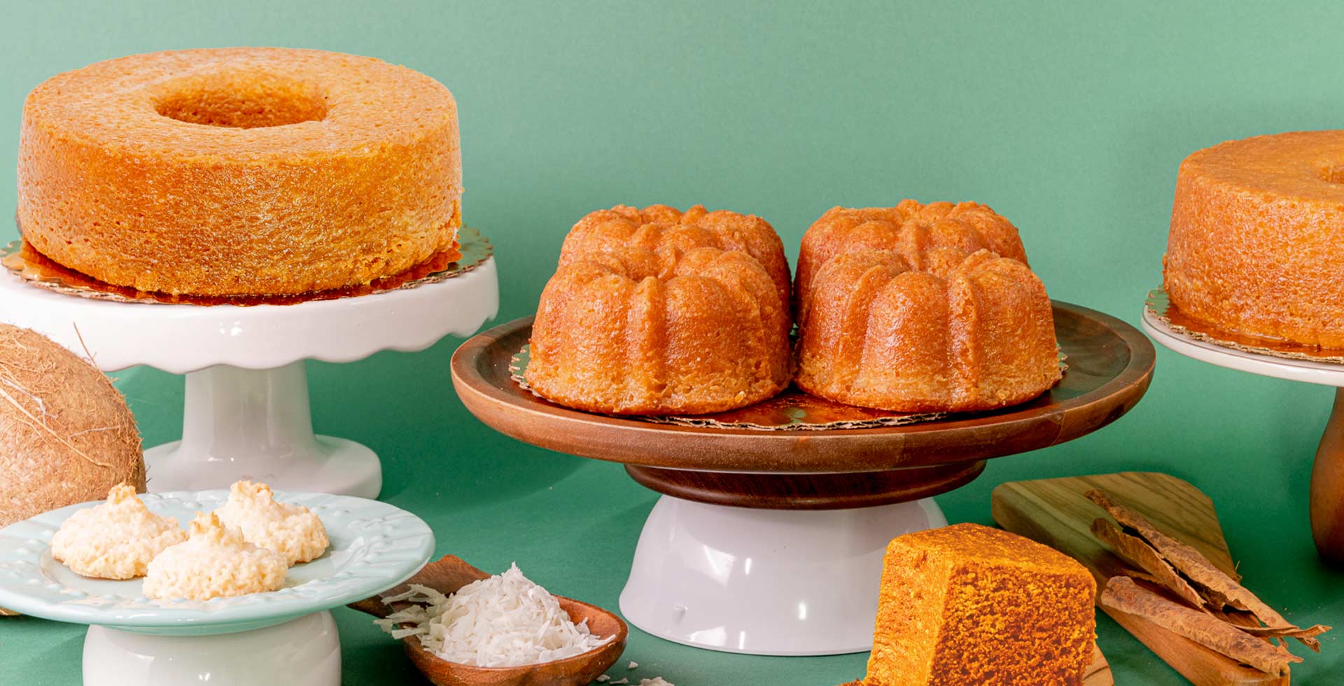 Assorted cakes on stands against a green background