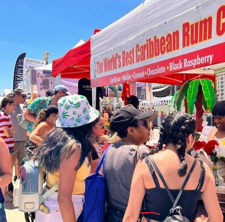 People at an outdoor event with a 'World's Best Caribbean Rum' booth.