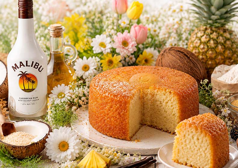 1lb malibu rum cake on a floral background with a rum bottle flowers and coconuts