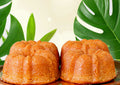 Two bundt cakes on a plate with green leaves in the background