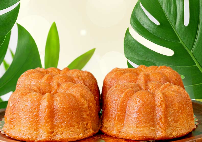 Two bundt cakes on a plate with green leaves in the background