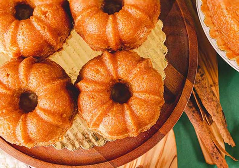 Baked goods in a bundt cake pan on a wooden board with a green background