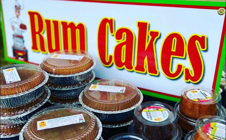 Display of rum cakes with a colorful sign in the background