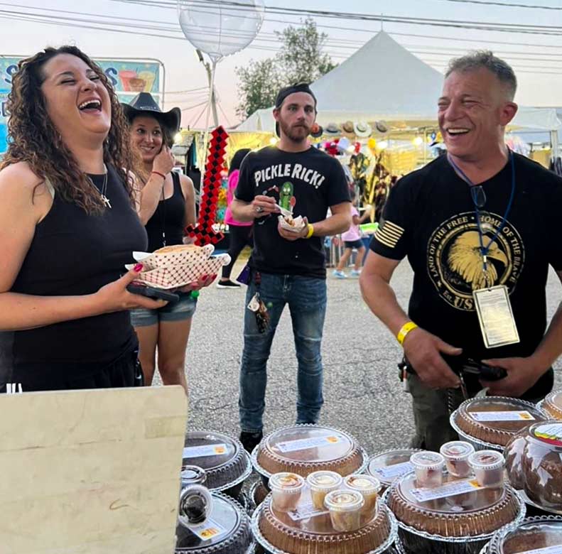 People at an outdoor event with baked goods on a table